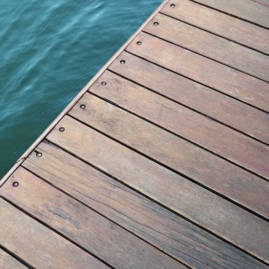 Wooden dock with rivets, next to turquoise water.