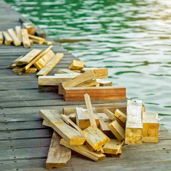 Pile of wooden blocks scattered on a dock beside green water