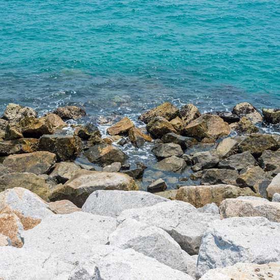 Rocky shoreline with turquoise seawater and large white boulders in the foreground