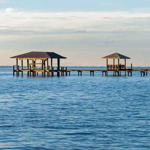 Two covered docks extend into blue water under a cloudy sky.