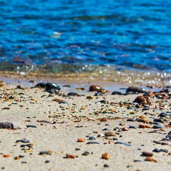 Pebbly sandy beach with blue ocean water in the background