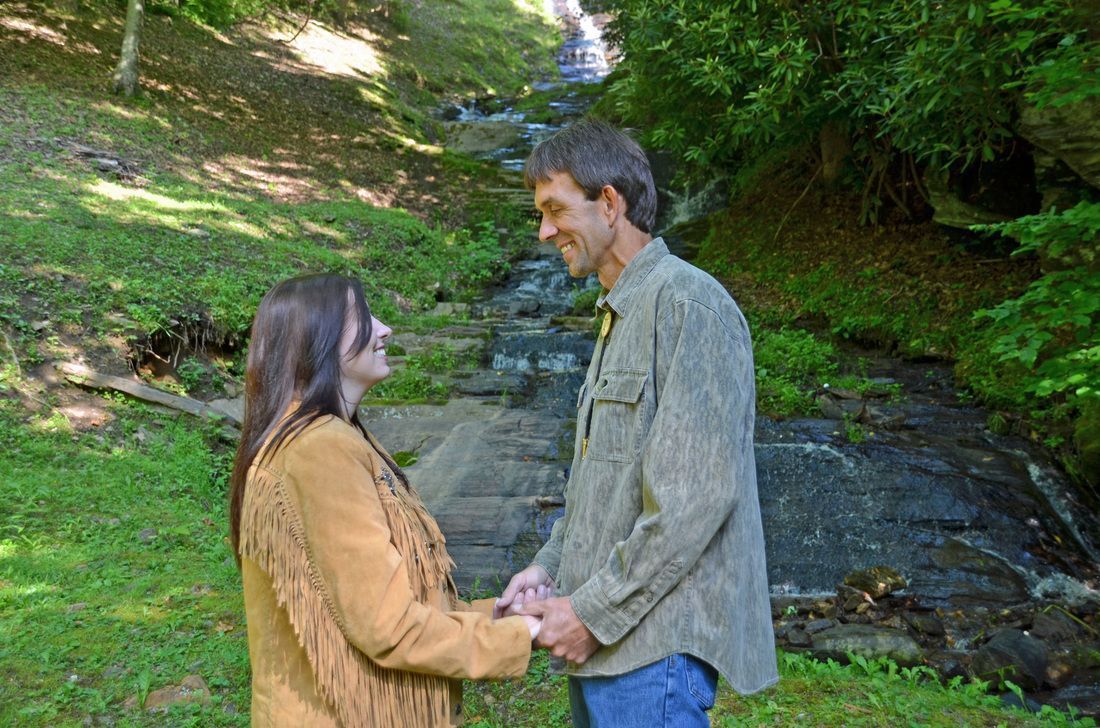 Two people holding hands on stone steps in a green wooded park
