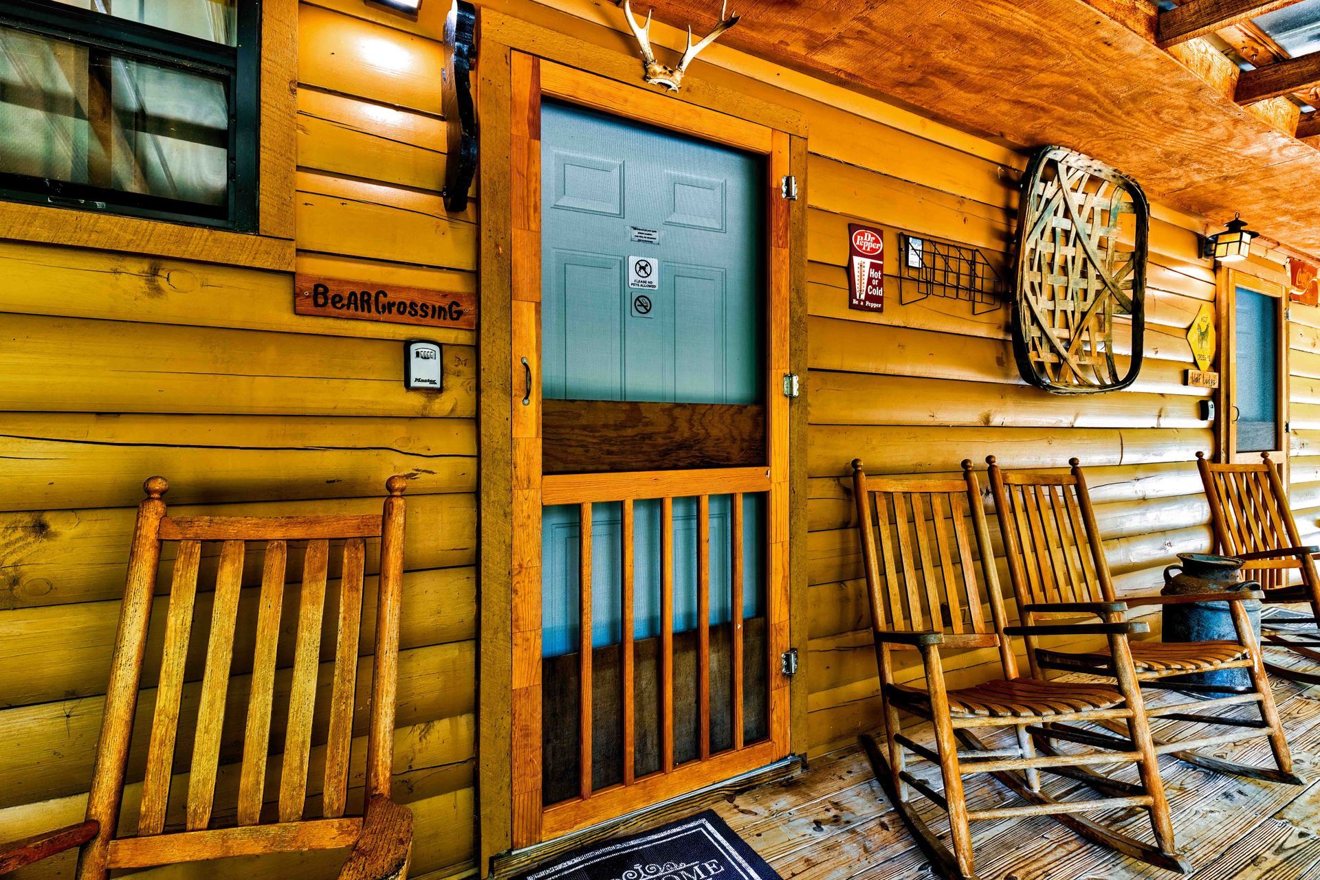 Rustic wooden porch with blue door, rocking chairs, and wall decor on a log cabin exterior