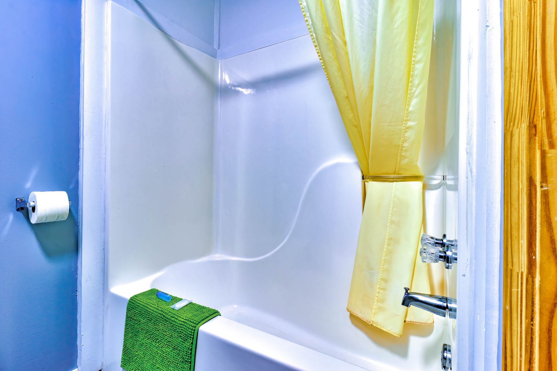 Bathroom with white tub, yellow shower curtain, green towel, and blue walls