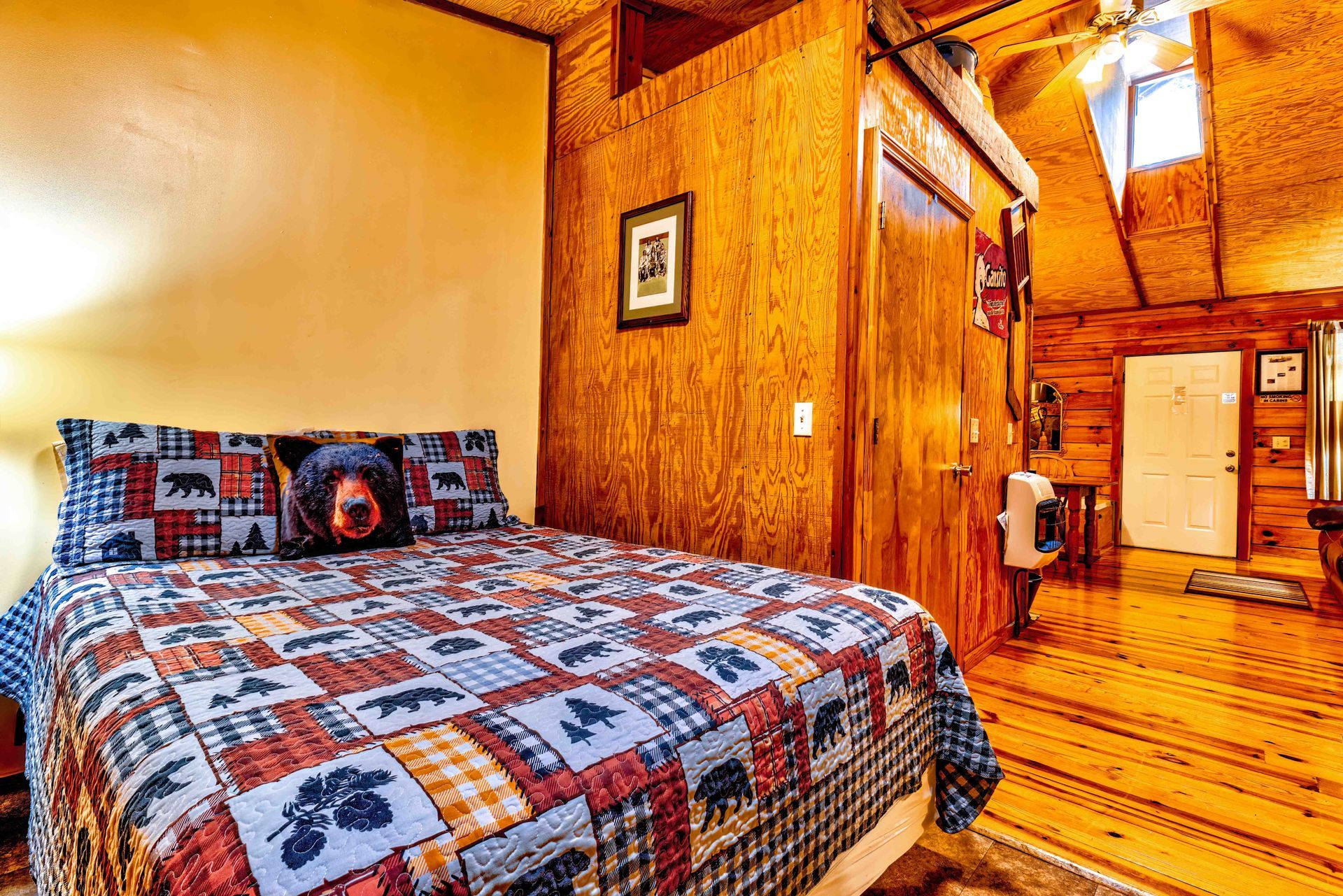 Cozy log cabin bedroom with quilted bed, wooden walls, and a hallway leading to another room