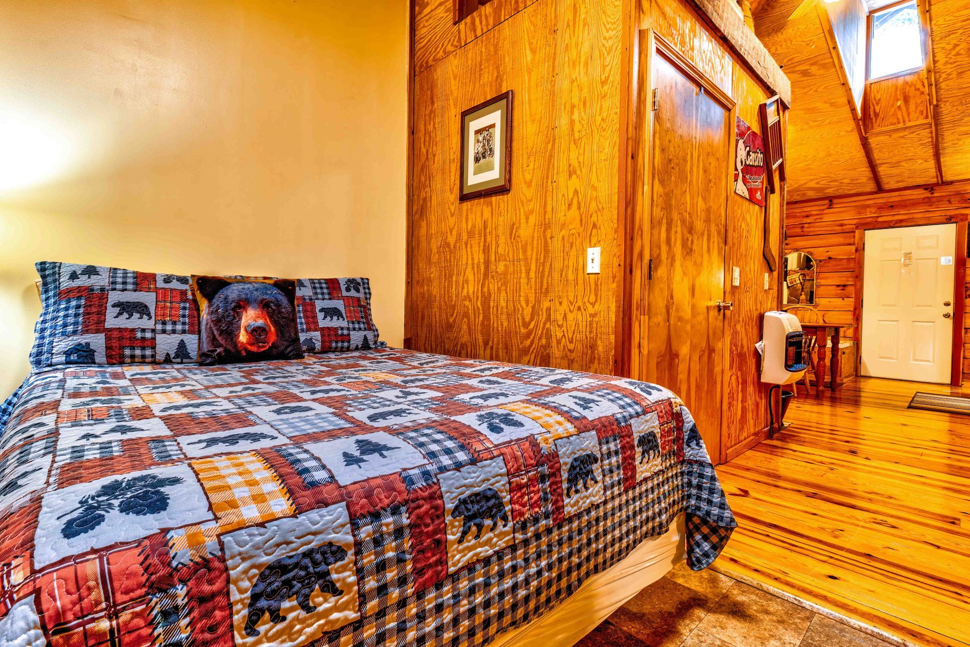 Cozy log-cabin bedroom with a patchwork quilt, wood-paneled walls, and a small doorway in the corner