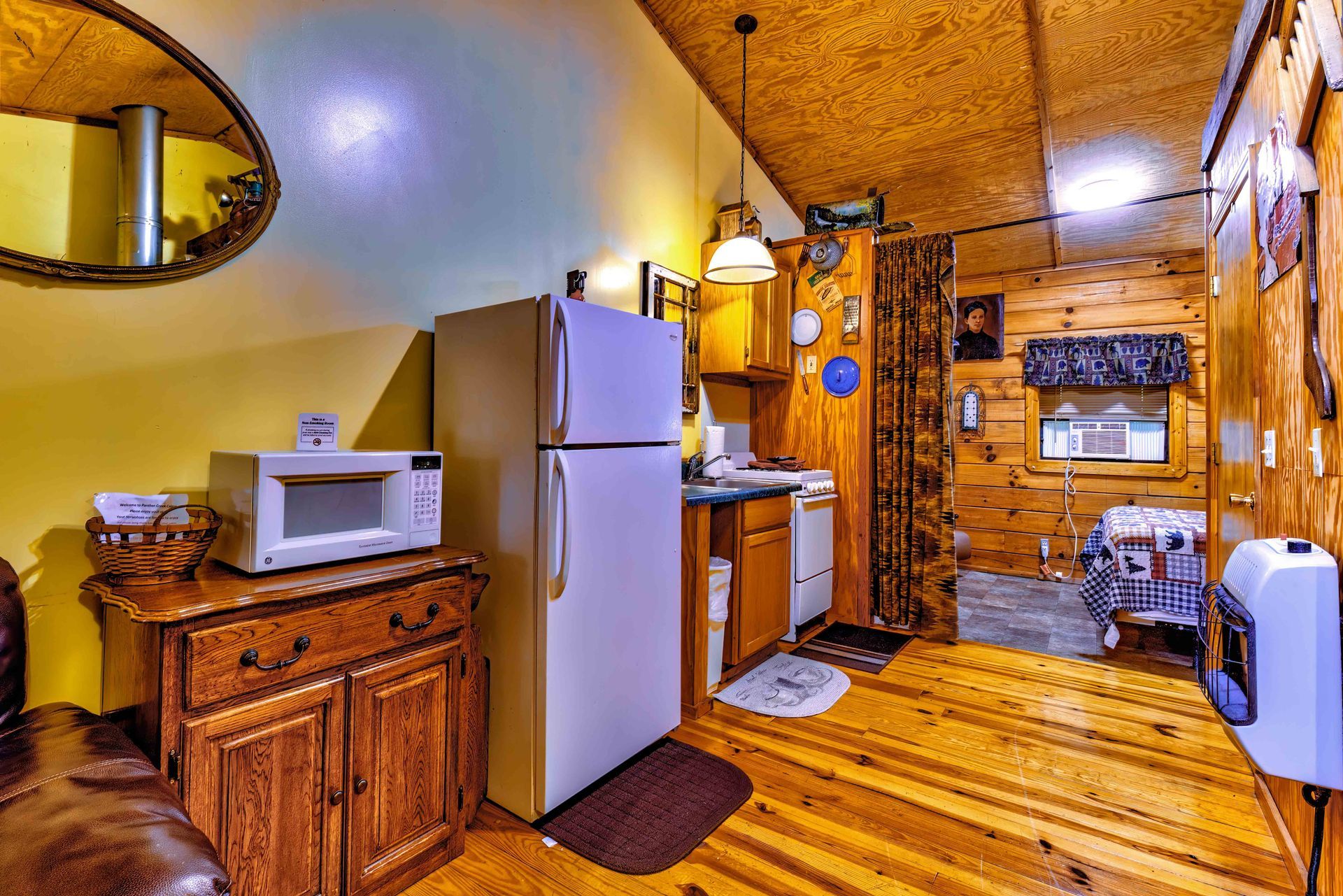 Cozy yellow kitchen with white fridge, microwave, wooden cabinets, and rustic wood-paneled walls