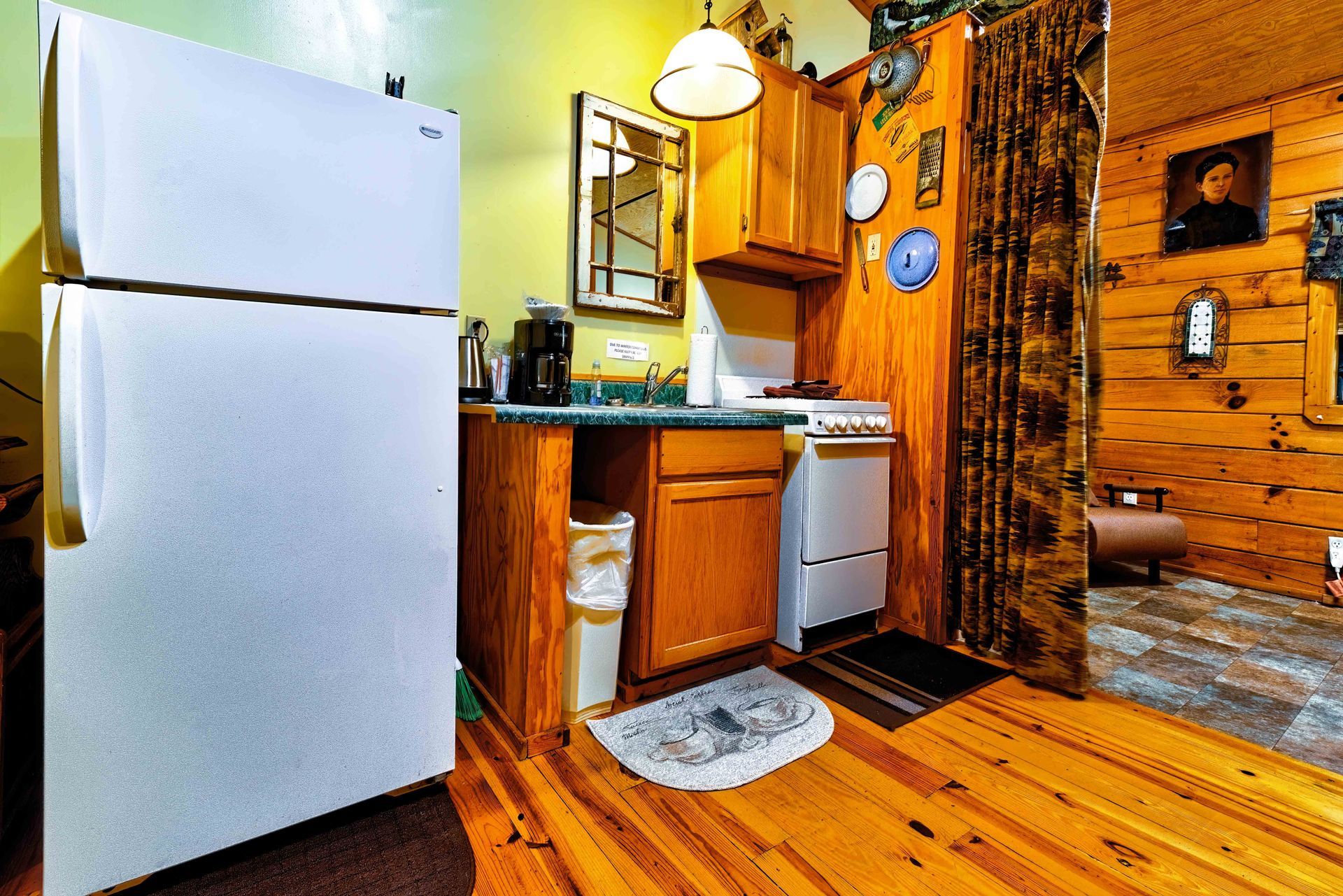 Cozy rustic kitchen with white fridge, wooden cabinets, sink, and warm wood floors