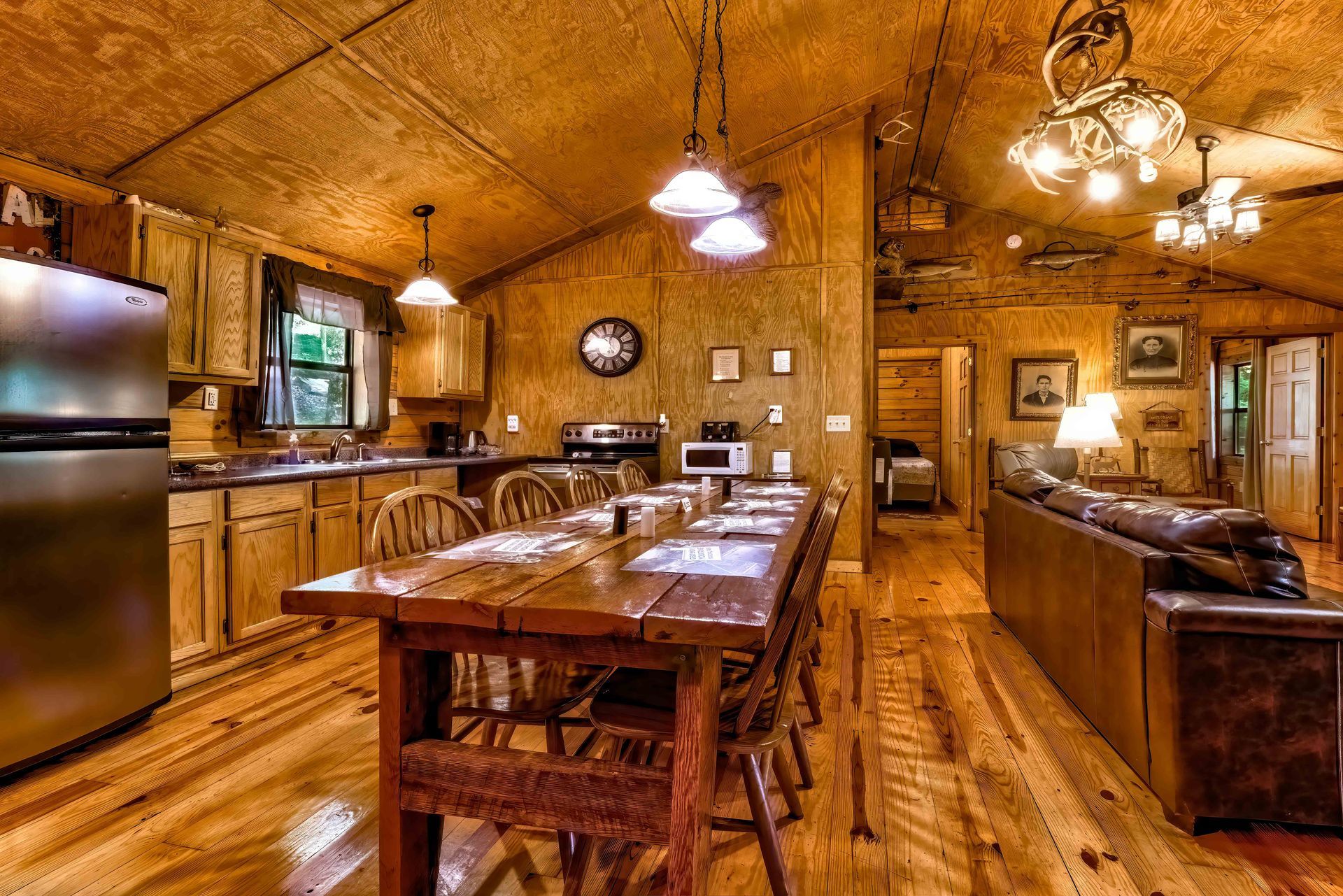 Rustic wooden cabin kitchen and dining area with long table, bar stools, and warm pendant lights