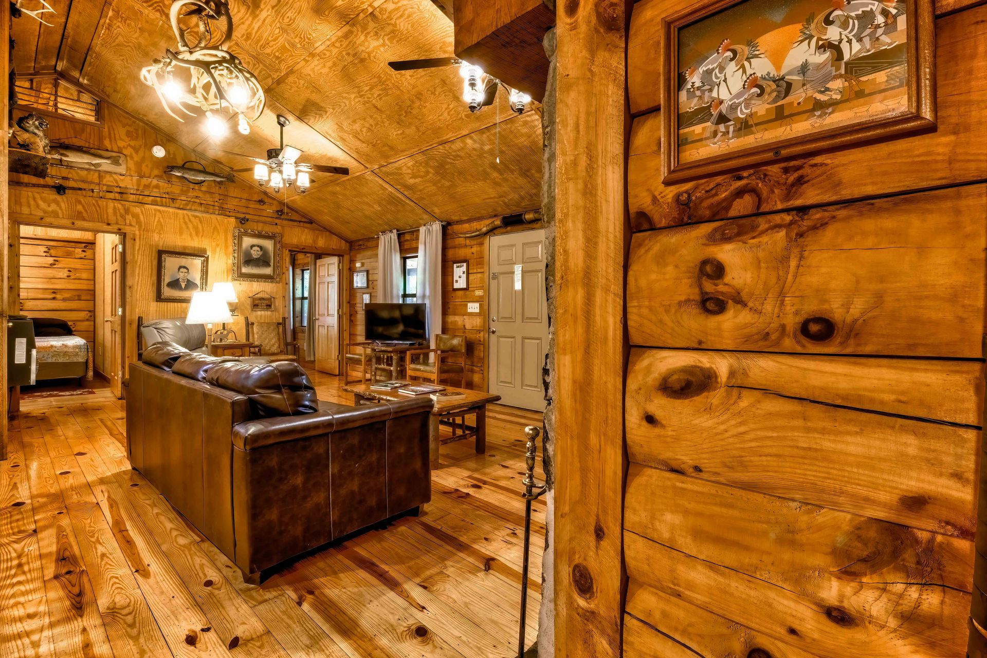 Rustic log cabin kitchen with wooden cabinets, island, and warm amber lighting