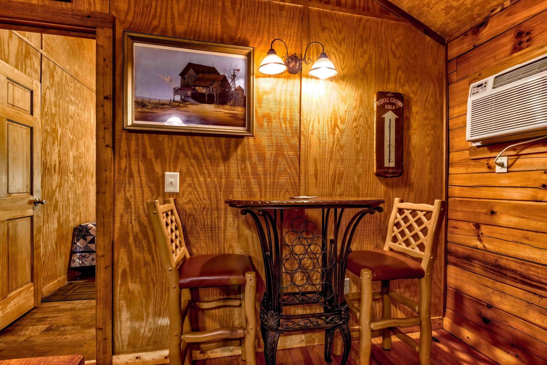 Cozy wood-paneled nook with two chairs, small table, framed art, and wall sconce lighting