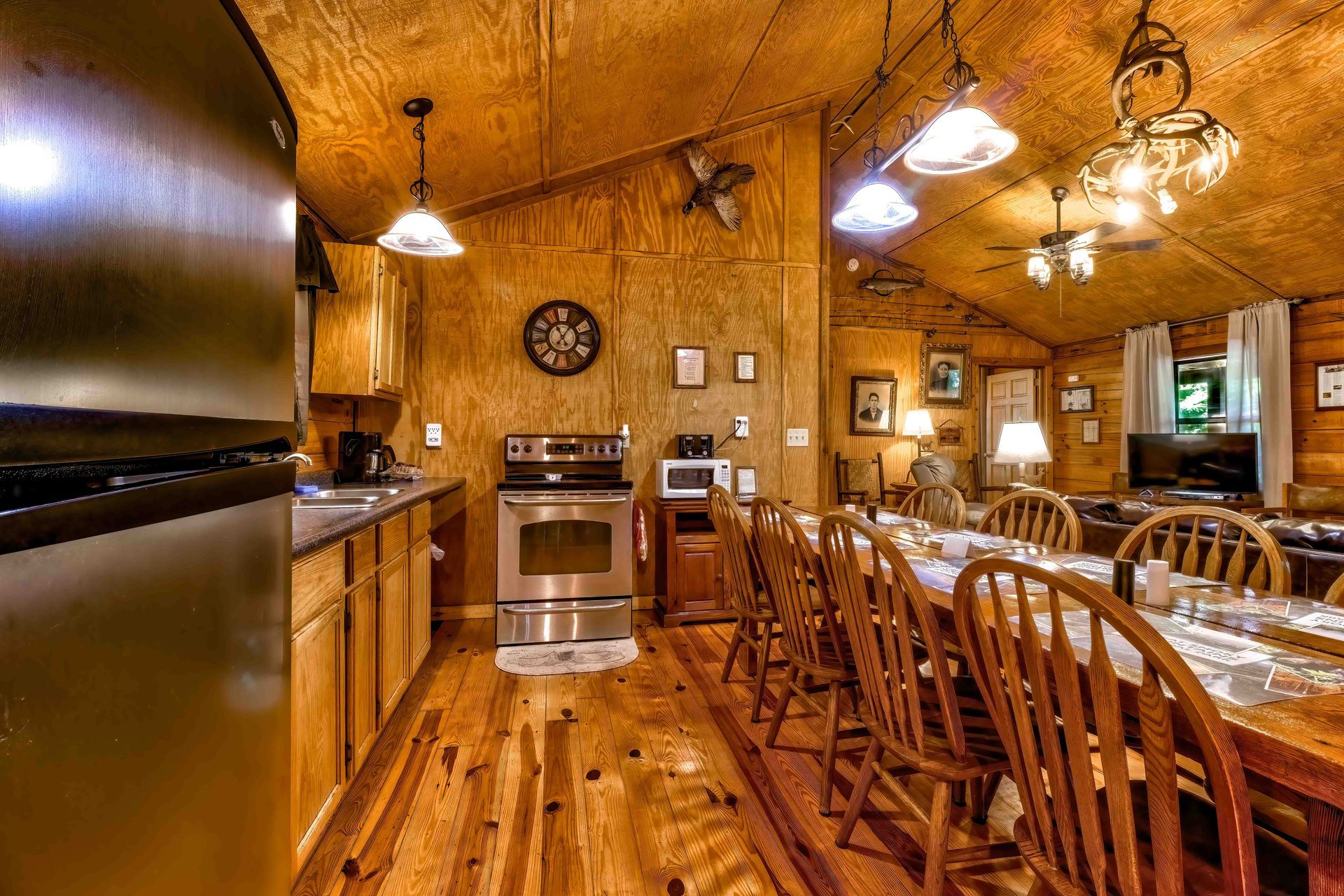 Rustic wooden dining room and kitchen with warm lighting, tables, chairs, and stone walls