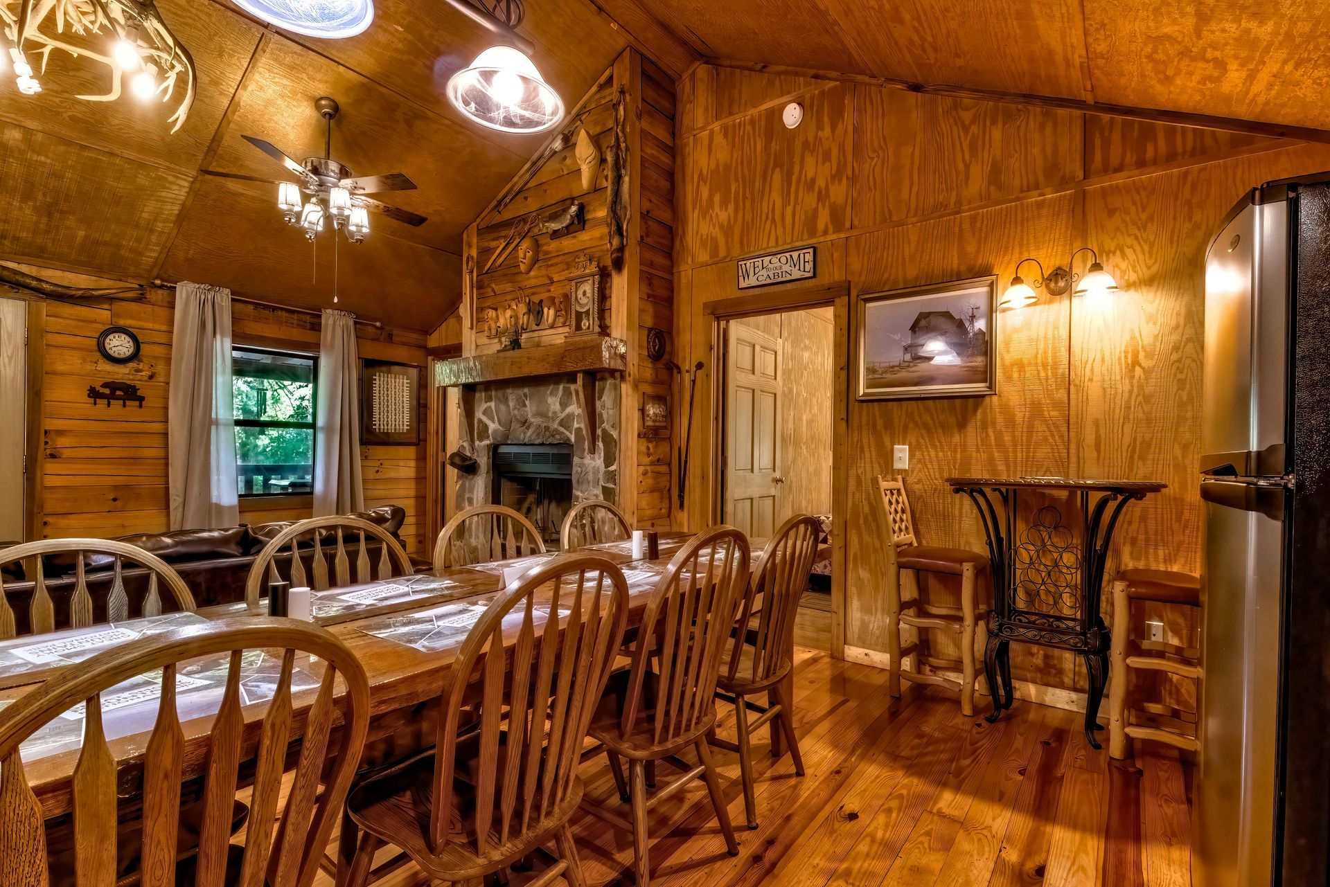 Rustic wooden dining room with tables, chairs, warm pendant lights, and a bar counter