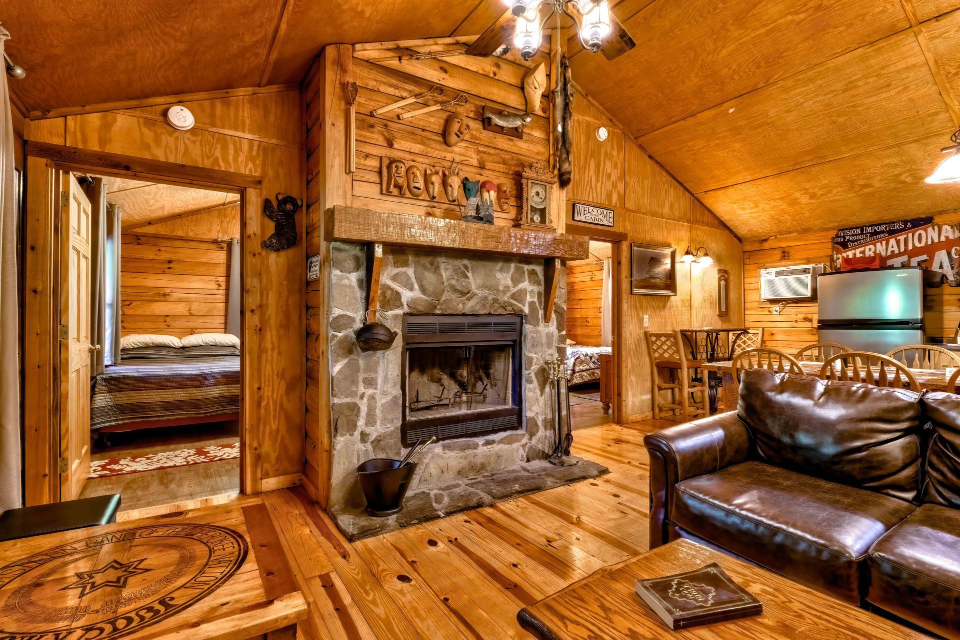 Cozy log cabin living room with stone fireplace, leather sofa, and warm wood-paneled walls