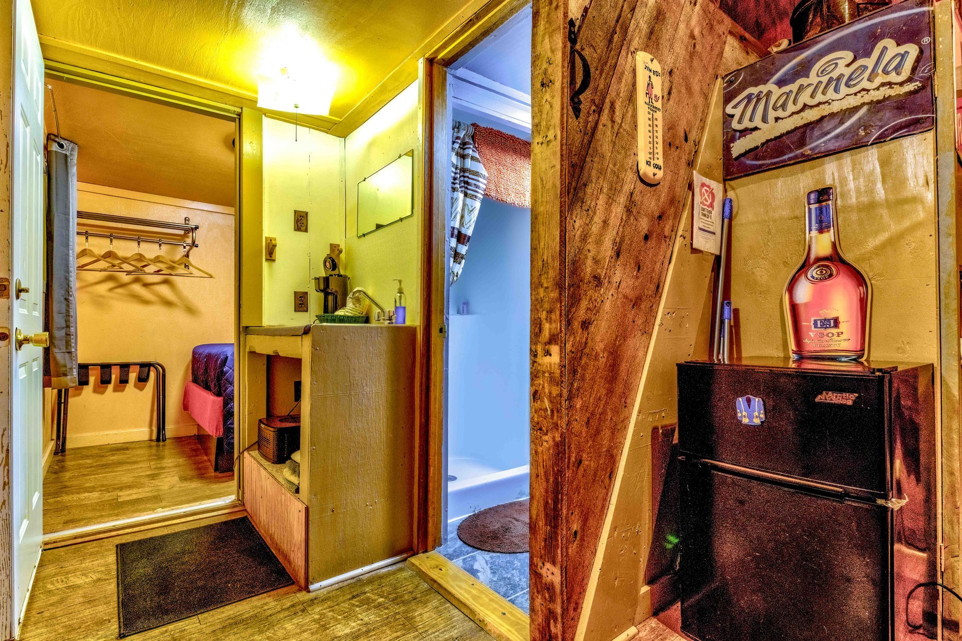 Small hallway with wood-paneled walls, a bench, and a doorway to a room with a mirror and blue-lit shower.