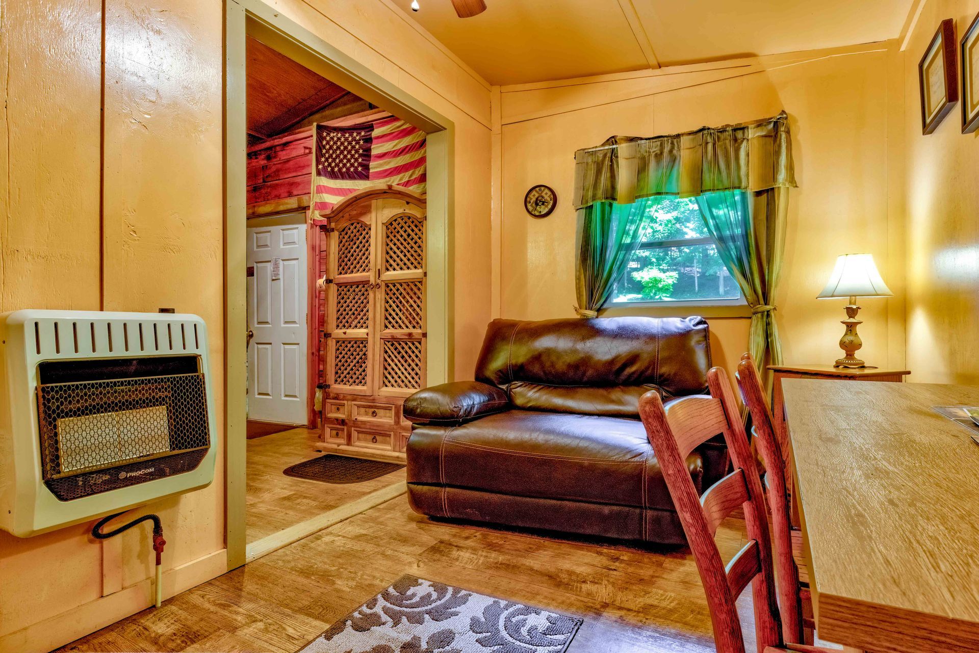 Cozy living room with leather chair, window, lamp, and warm wood-paneled walls