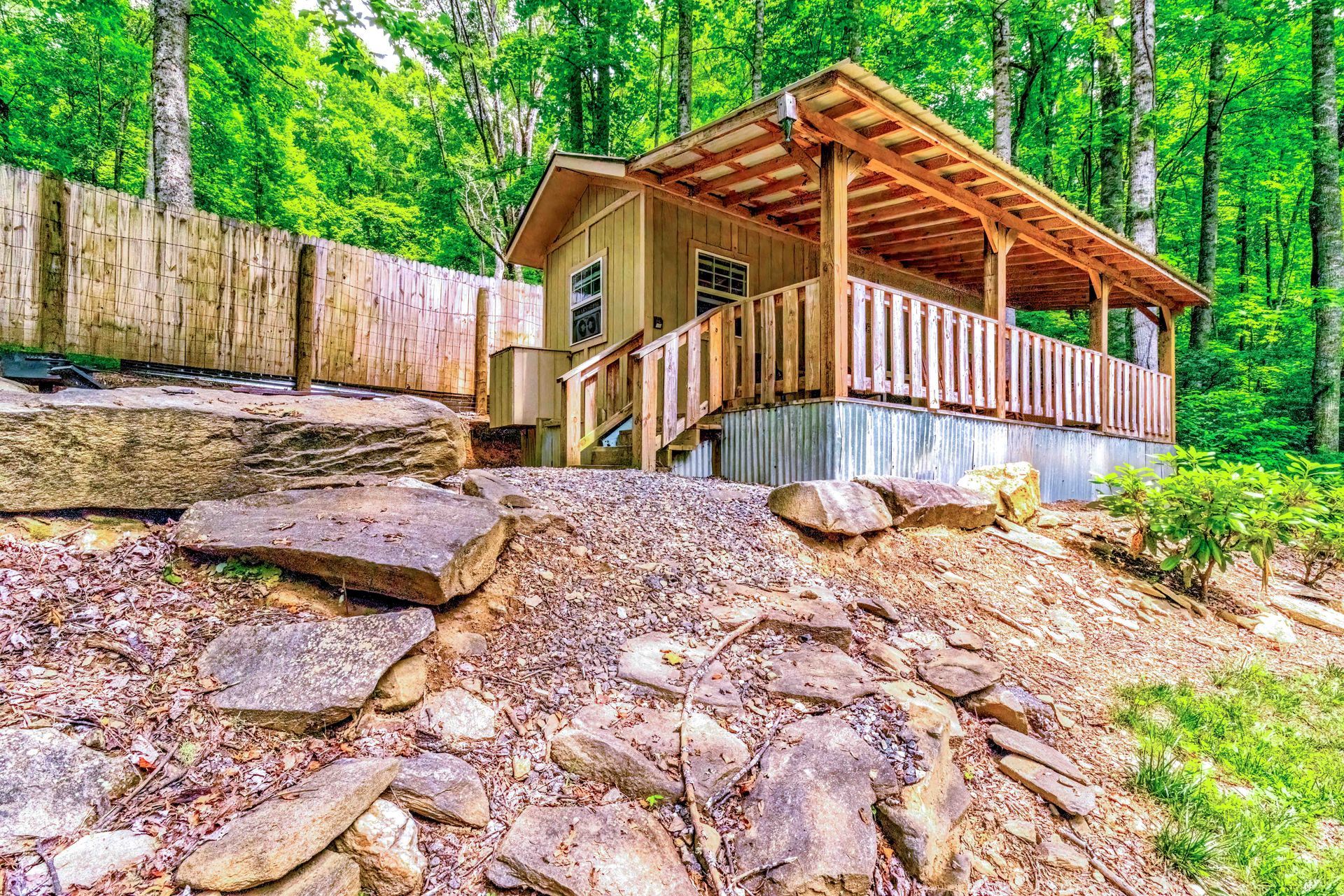 Rustic cabin with a covered porch on a rocky wooded hillside