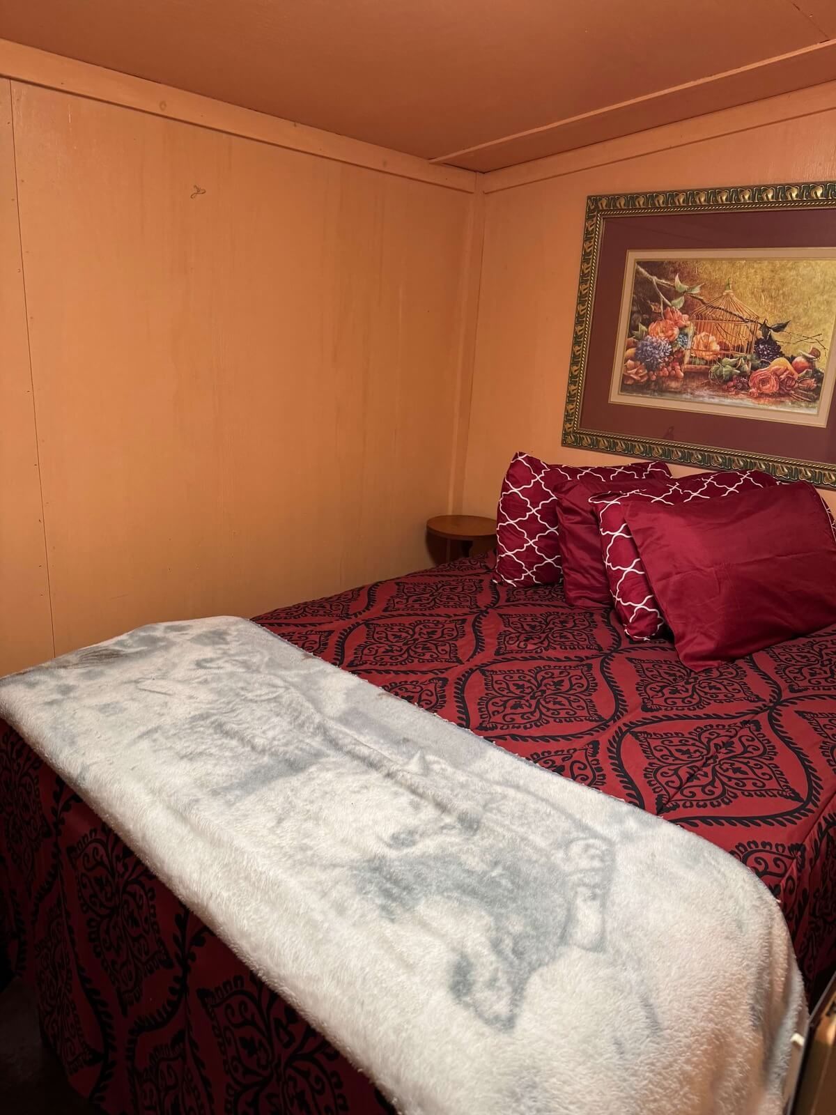 Cozy bedroom with a bed covered in red patterned bedding, a gray blanket, and wall art above the headboard