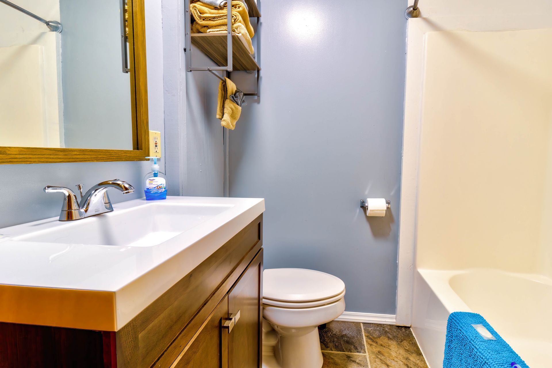 Small bathroom with sink, toilet, and bathtub/shower, featuring blue walls and beige decor