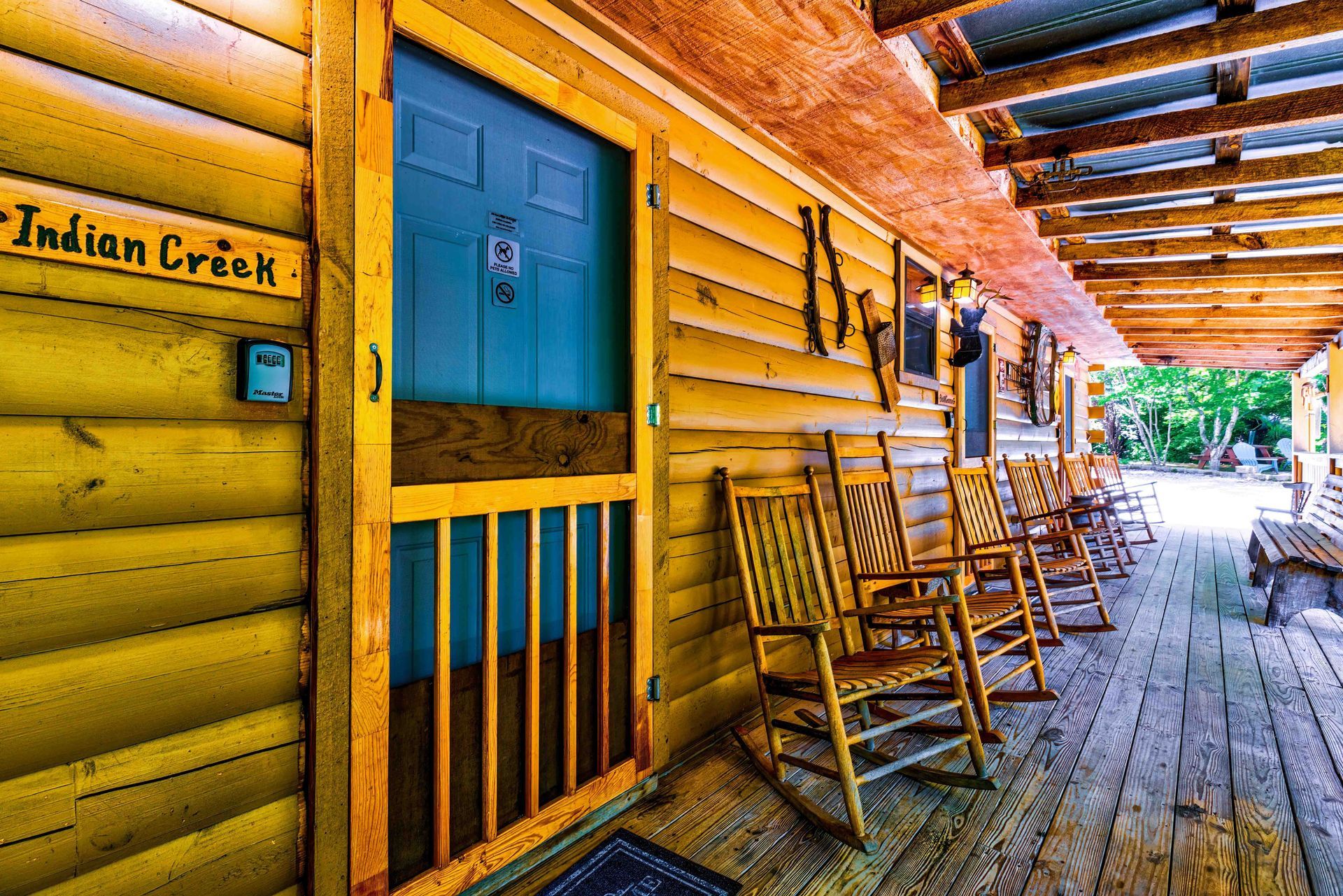 Yellow log cabin porch with rocking chairs and blue door, labeled Indian Creek