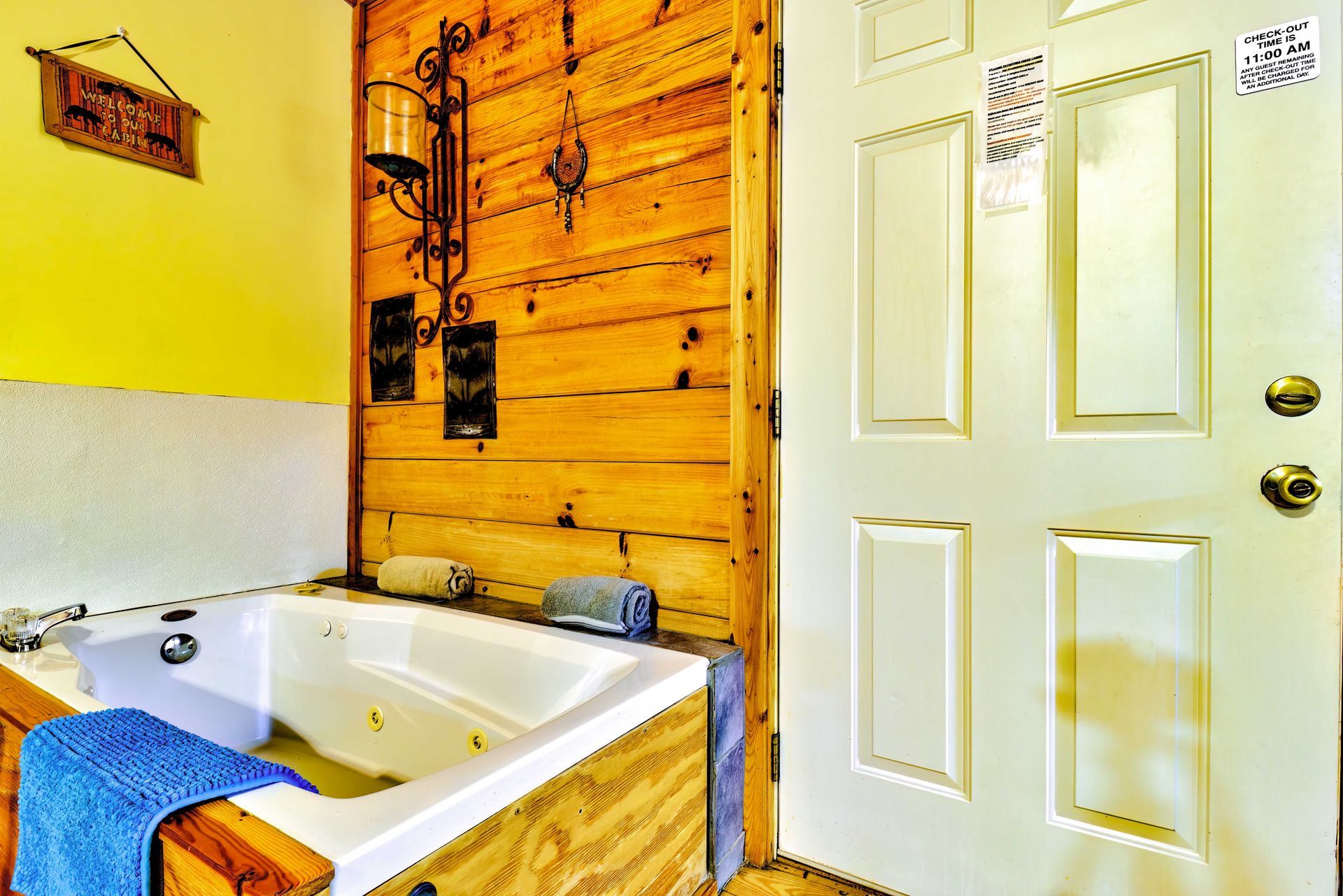 Bright bathroom with a white tub, wood-paneled wall, and white door