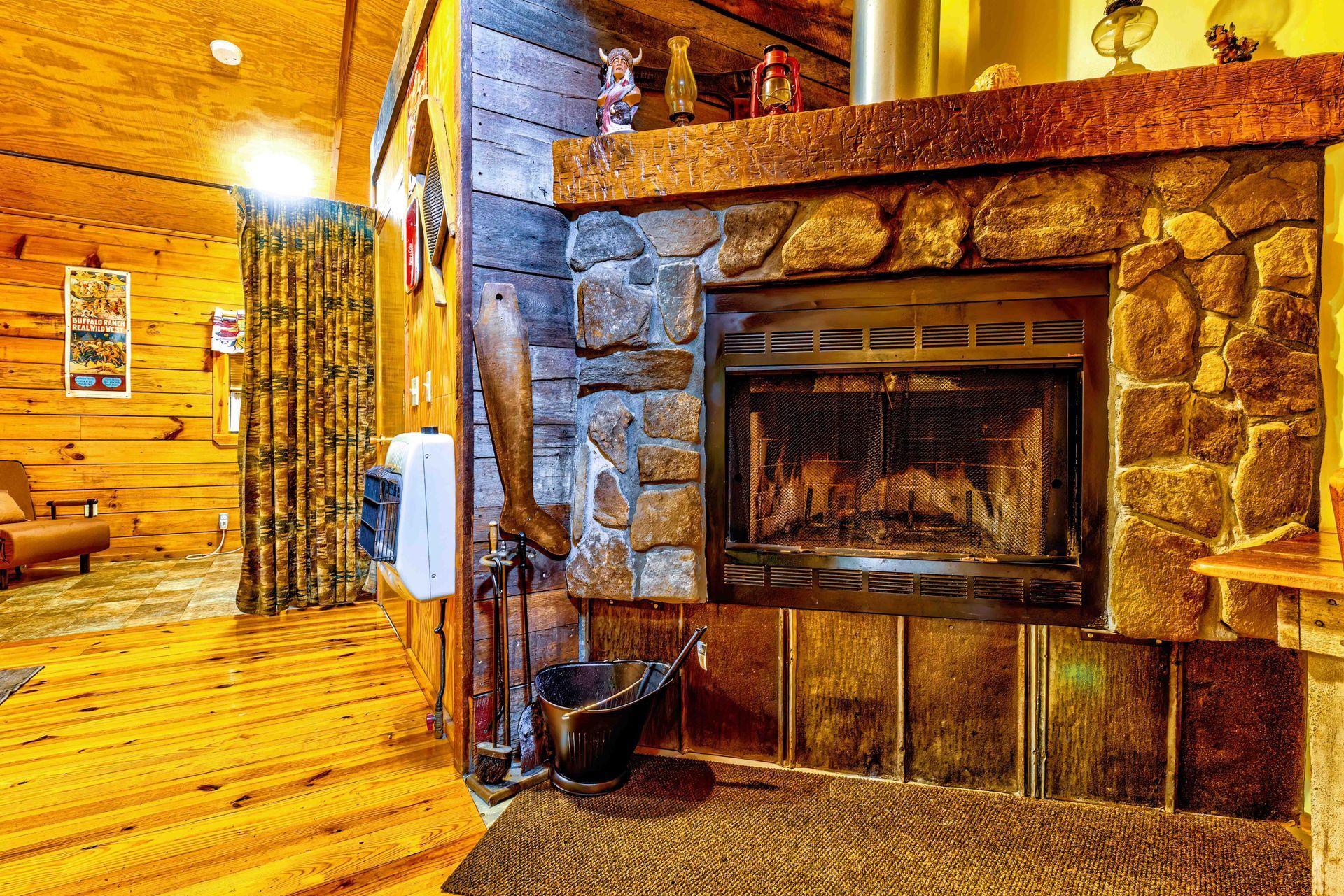 Rustic lodge interior with a stone fireplace, wooden walls, and warm amber lighting