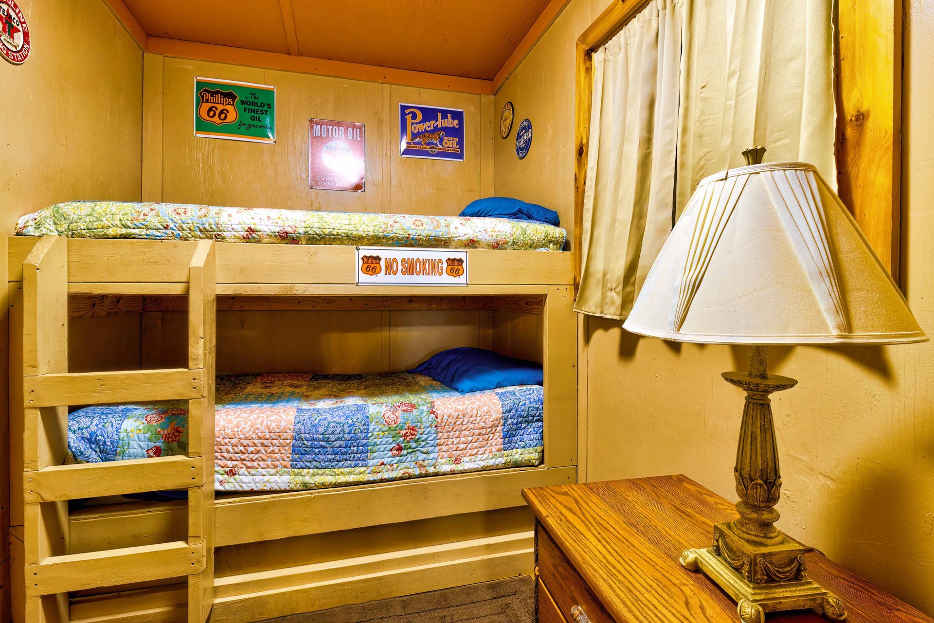 Cozy wood-paneled bedroom with bunk beds, a nightstand lamp, and warm yellow lighting