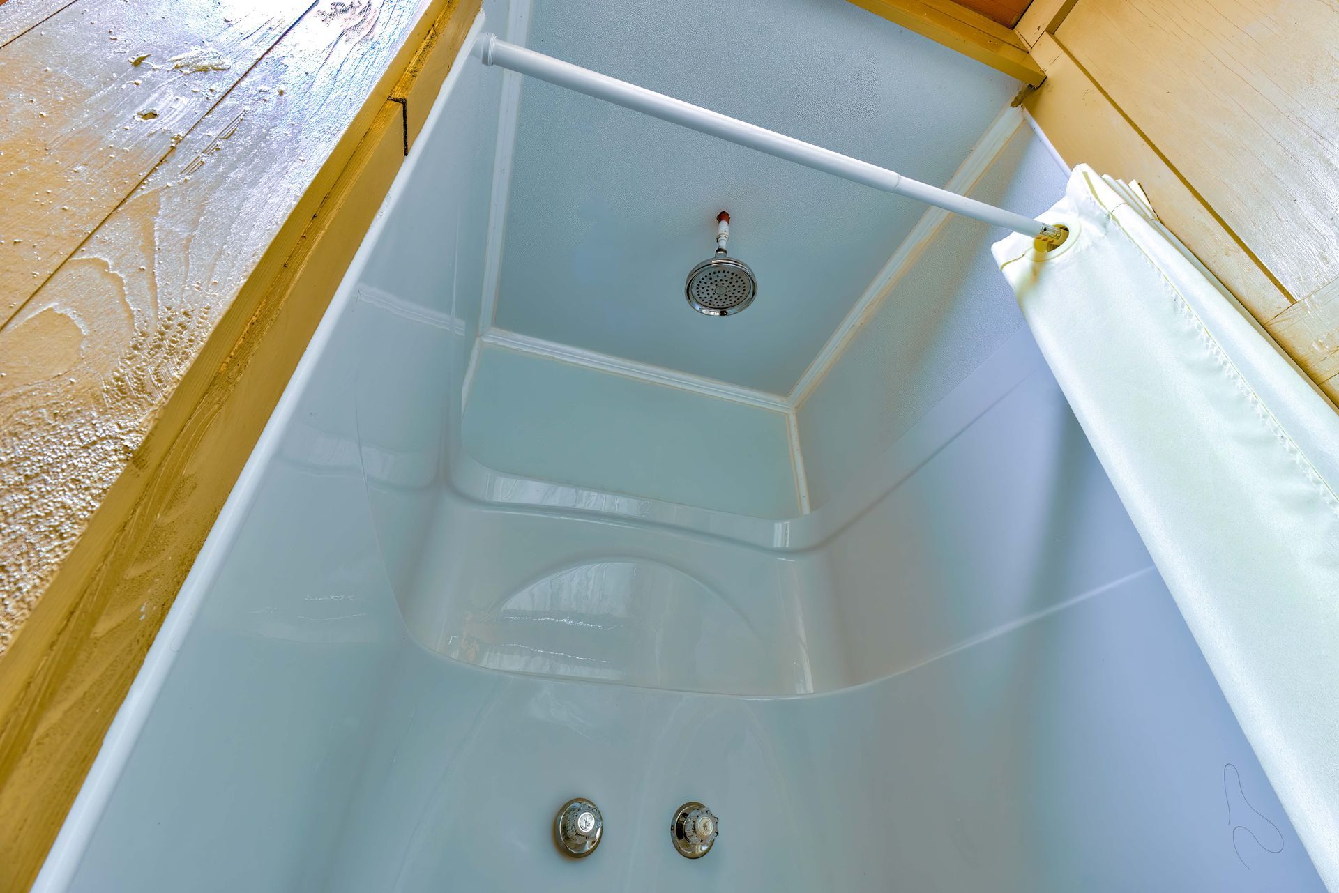 White bathtub viewed from above with blue water and showerhead