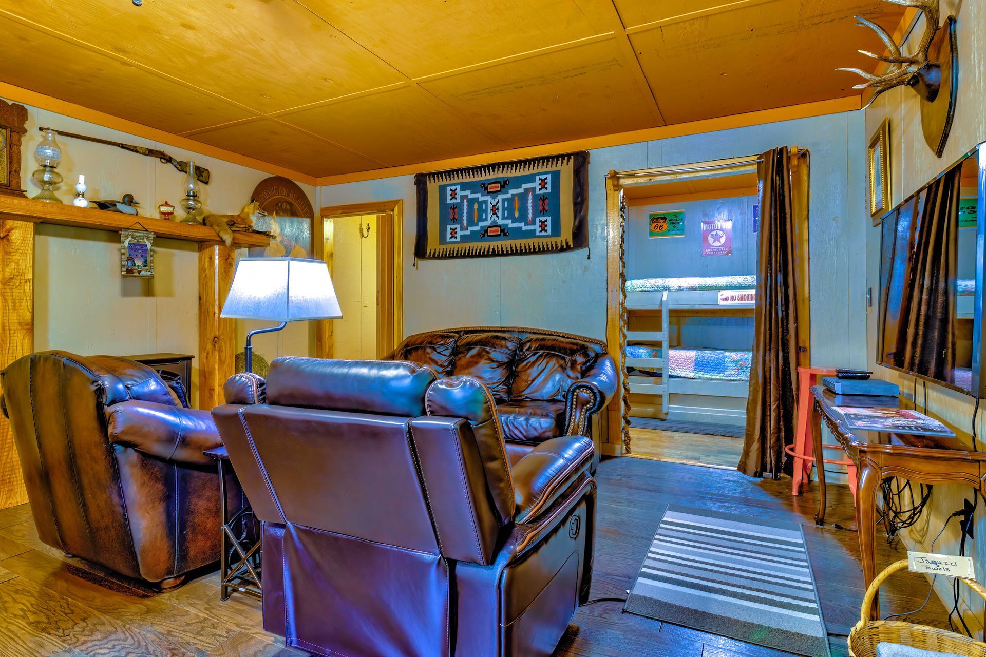 Cozy living room with leather sofas, fireplace, lamp, and TV above the mantel