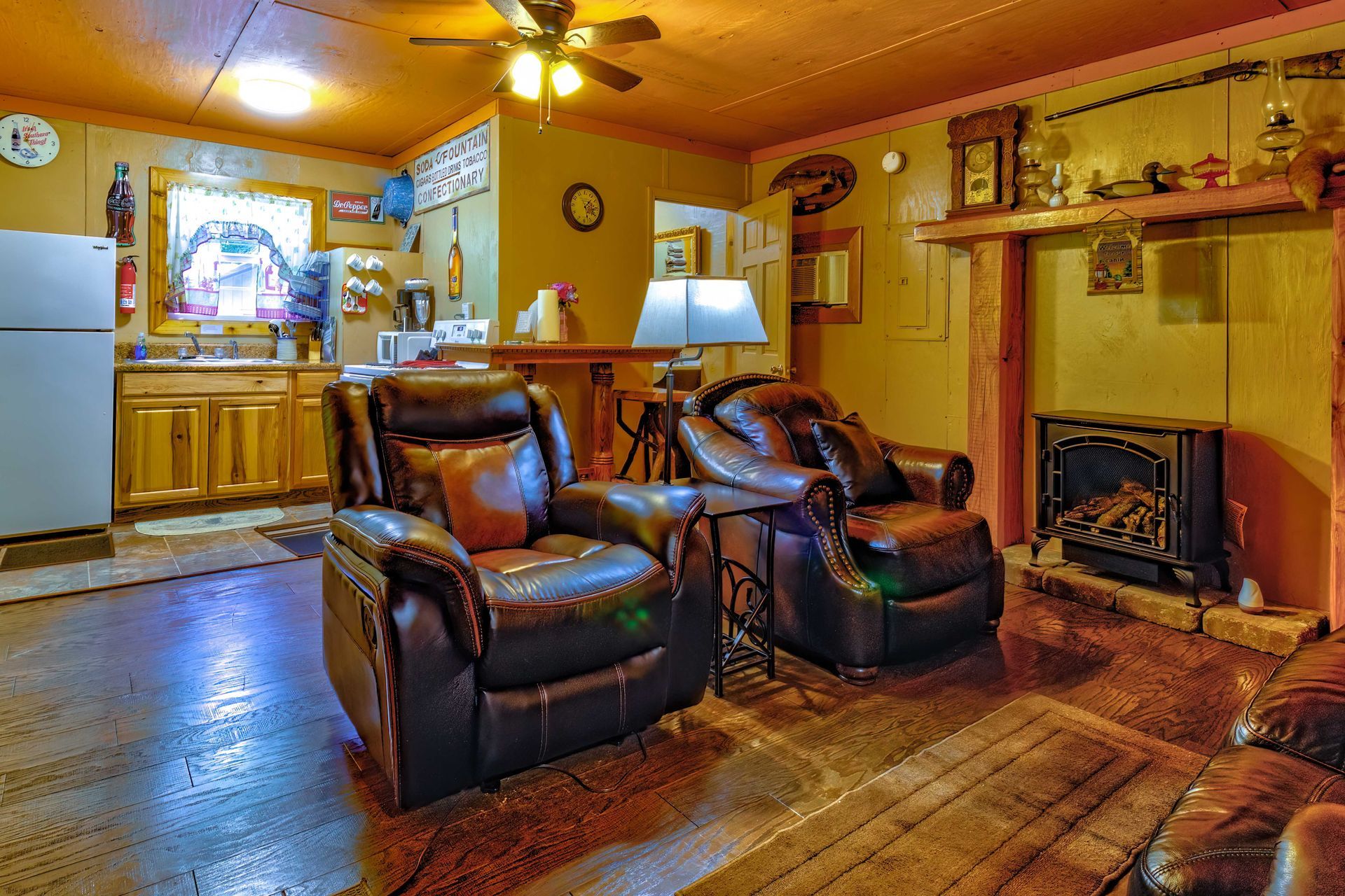 Cozy living room with two leather recliners, fireplace, wood floors, and warm yellow walls