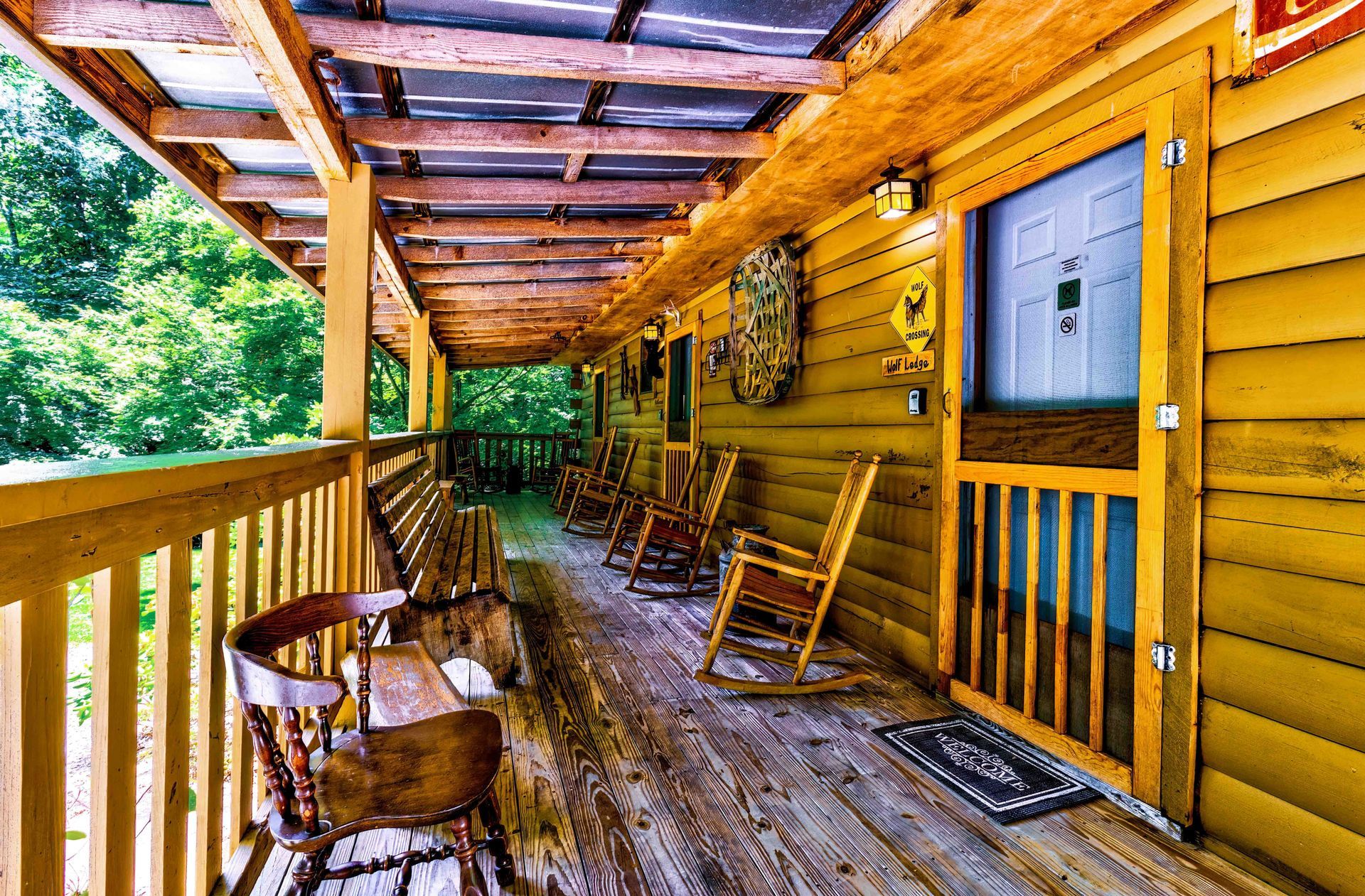 Wooden cabin porch with rocking chairs, log walls, and a view of green trees