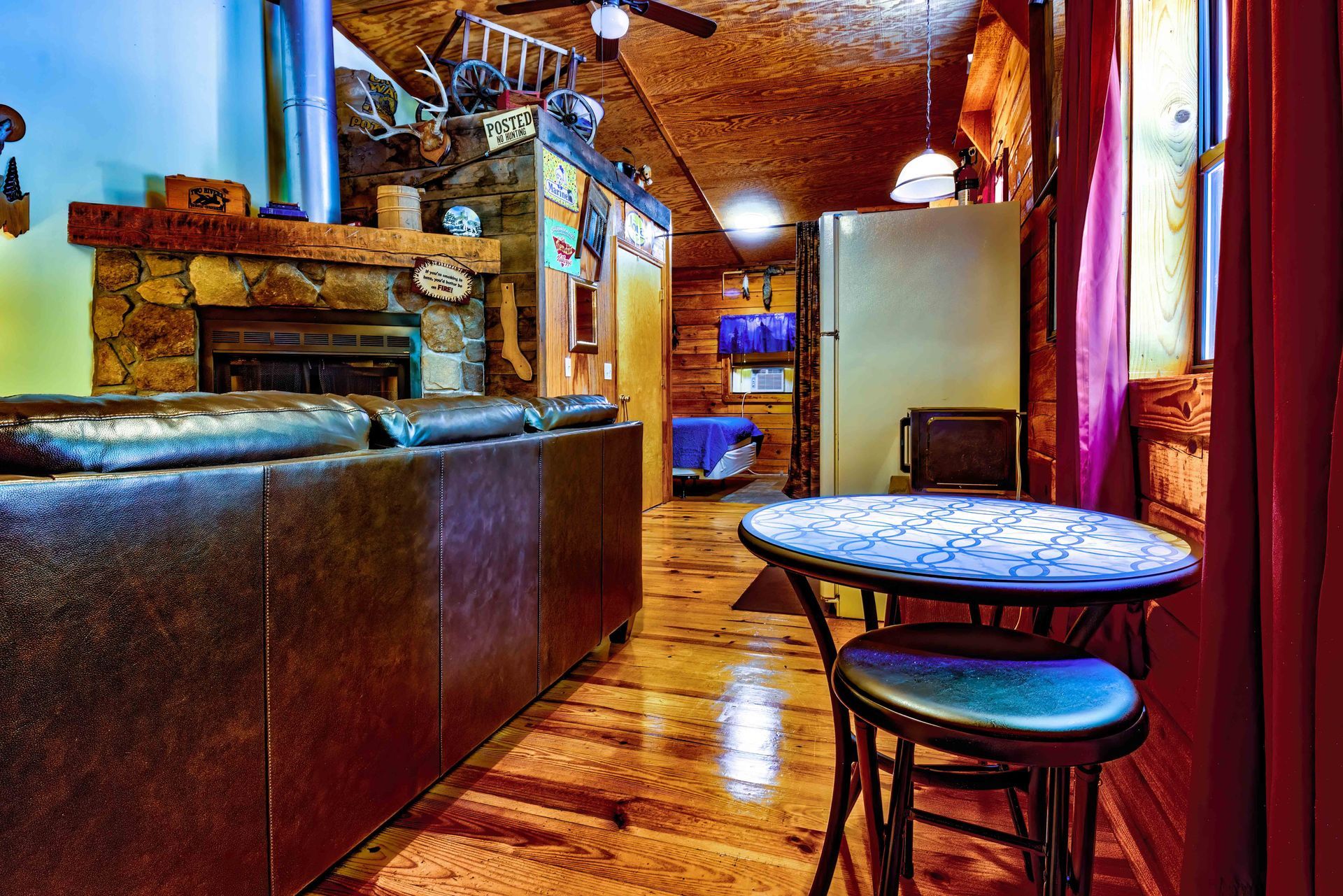 Cozy rustic room with leather booth, round table, wood floor, and exposed brick walls