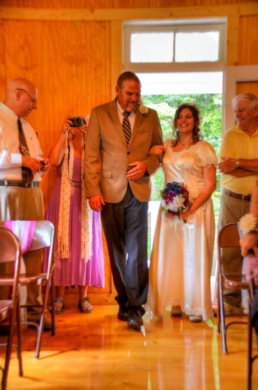 Bride and groom walking down an aisle in a wood-paneled room during an indoor wedding ceremony