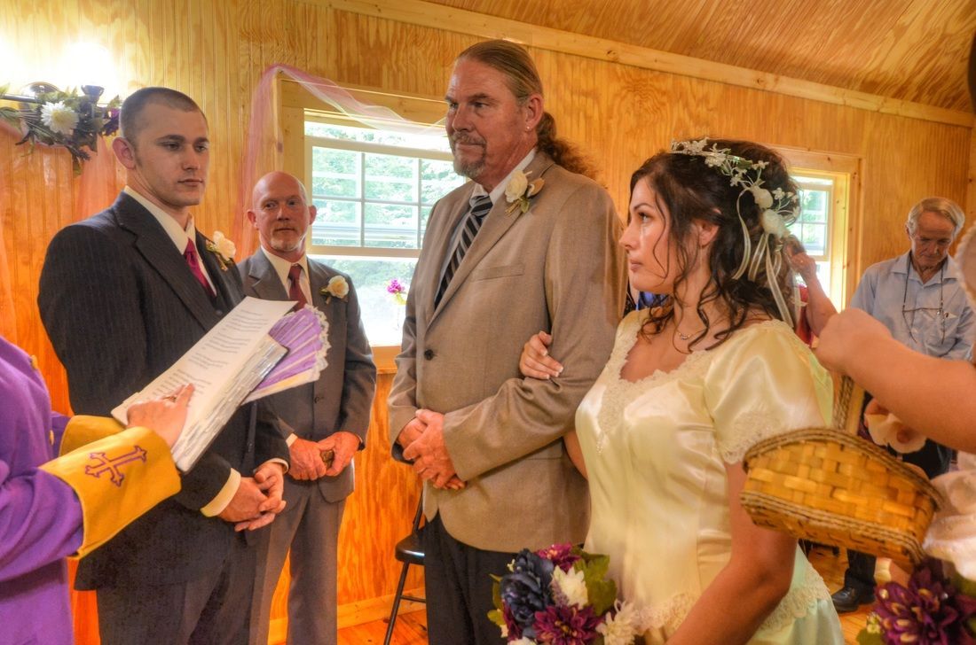 People gathered indoors for a ceremony, with two holding baskets and others exchanging papers.