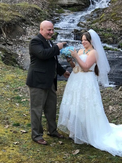 Bride and groom exchanging rings beside a waterfall outdoors