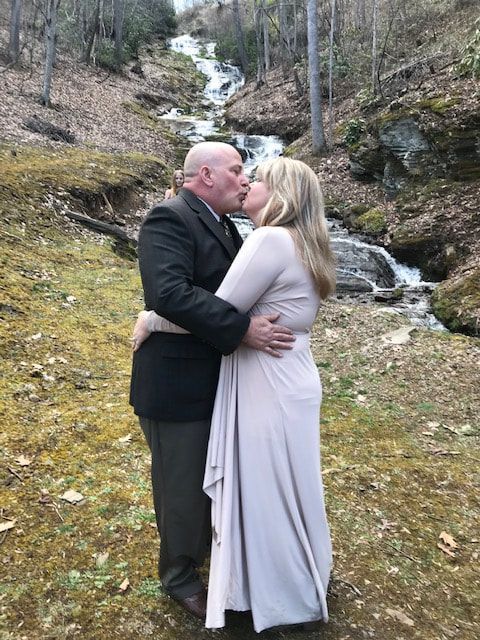 Couple kissing and embracing beside a small waterfall in a wooded area