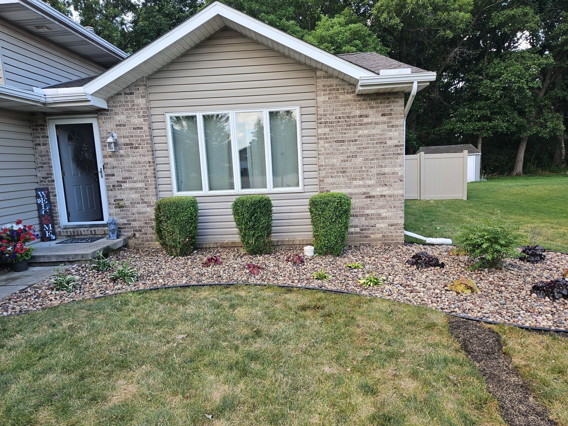 Backyard garden with raised ramp and white railing beside a wooden fence under a cloudy sky