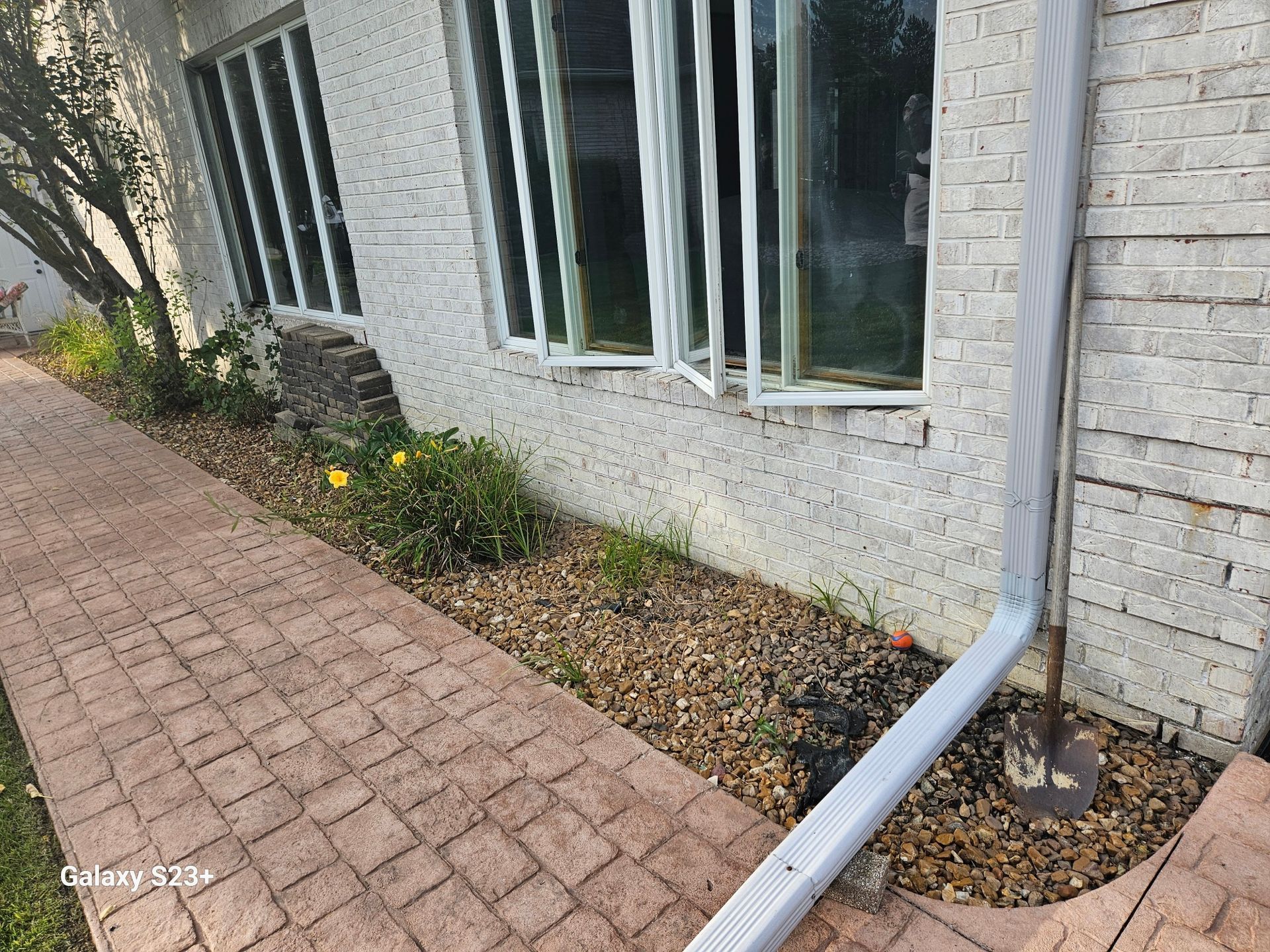 Suburban house patio with sliding glass doors, green lawn, and shrubs in front.