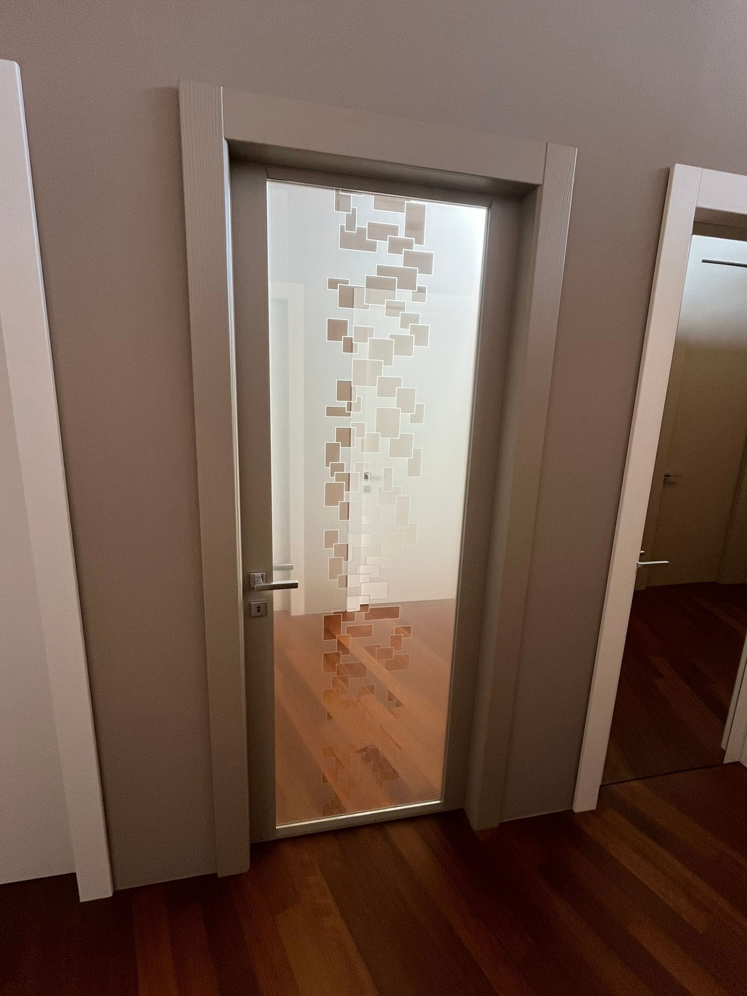 Specchio a parete che riflette un corridoio con porte bianche e pavimento in legno
