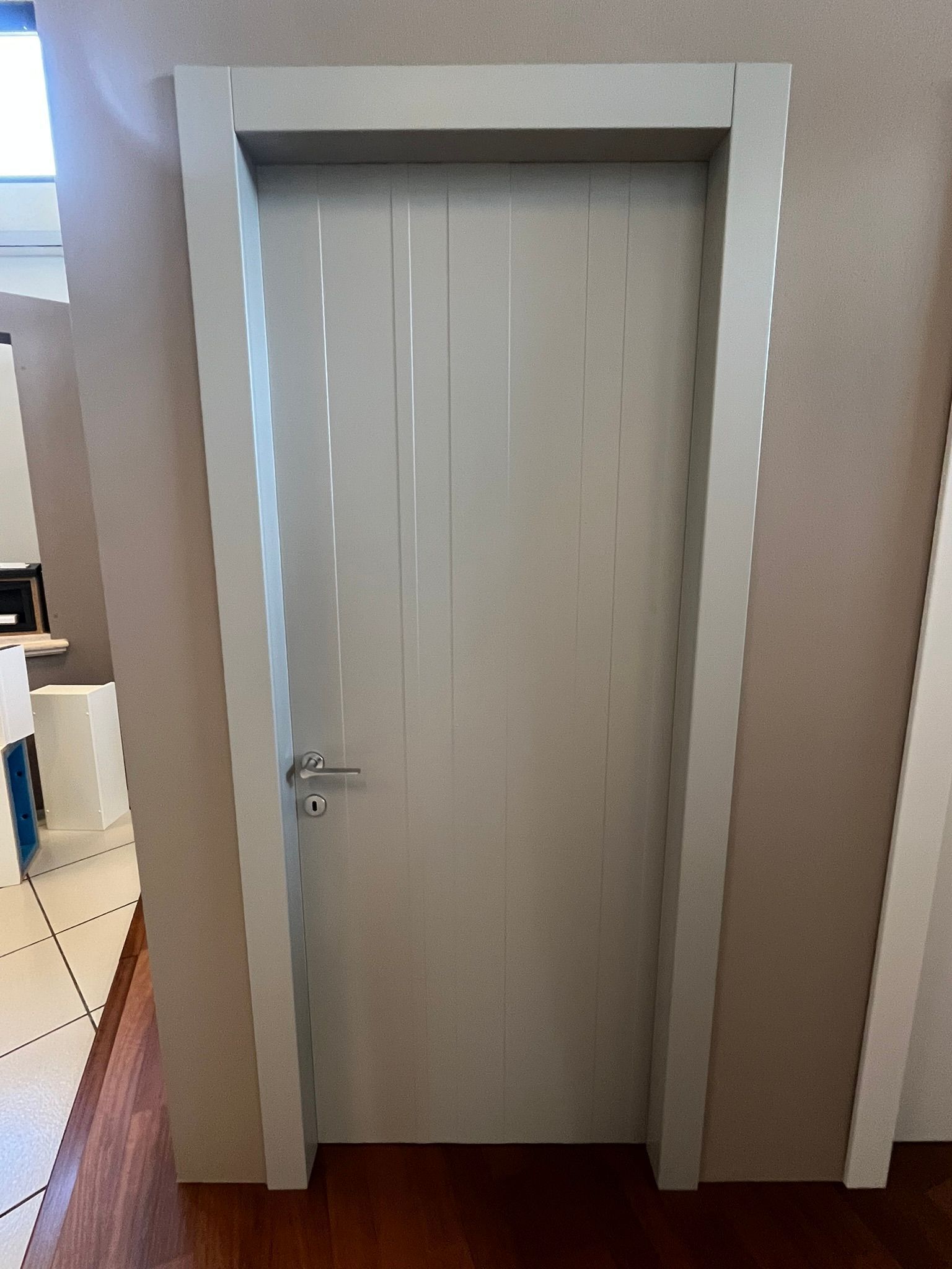 Porta bianca chiusa con maniglia argentata in un corridoio