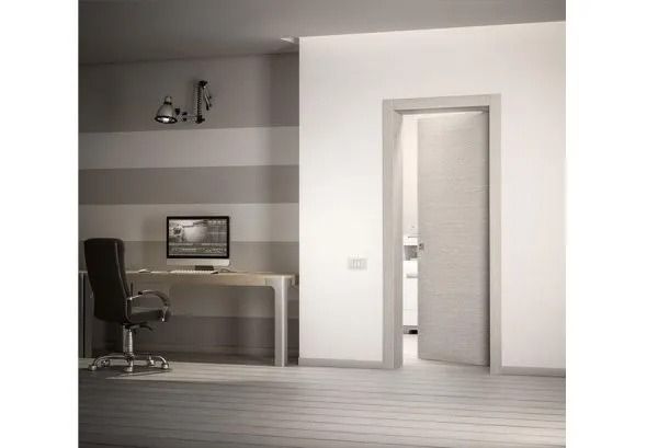 Stanza moderna e minimalista con scrivania, computer, sedia, parete a righe e porta aperta.