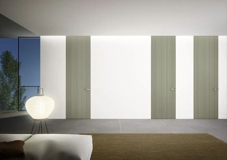 Stanza moderna e minimalista con pannelli a parete bianchi e verde chiaro, una lampada da terra e un tappeto.
