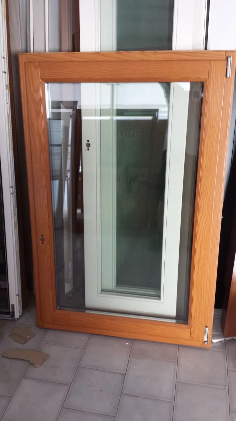 Porta o finestra con cornice in legno e vetro, appoggiata a una parete su un pavimento piastrellato.