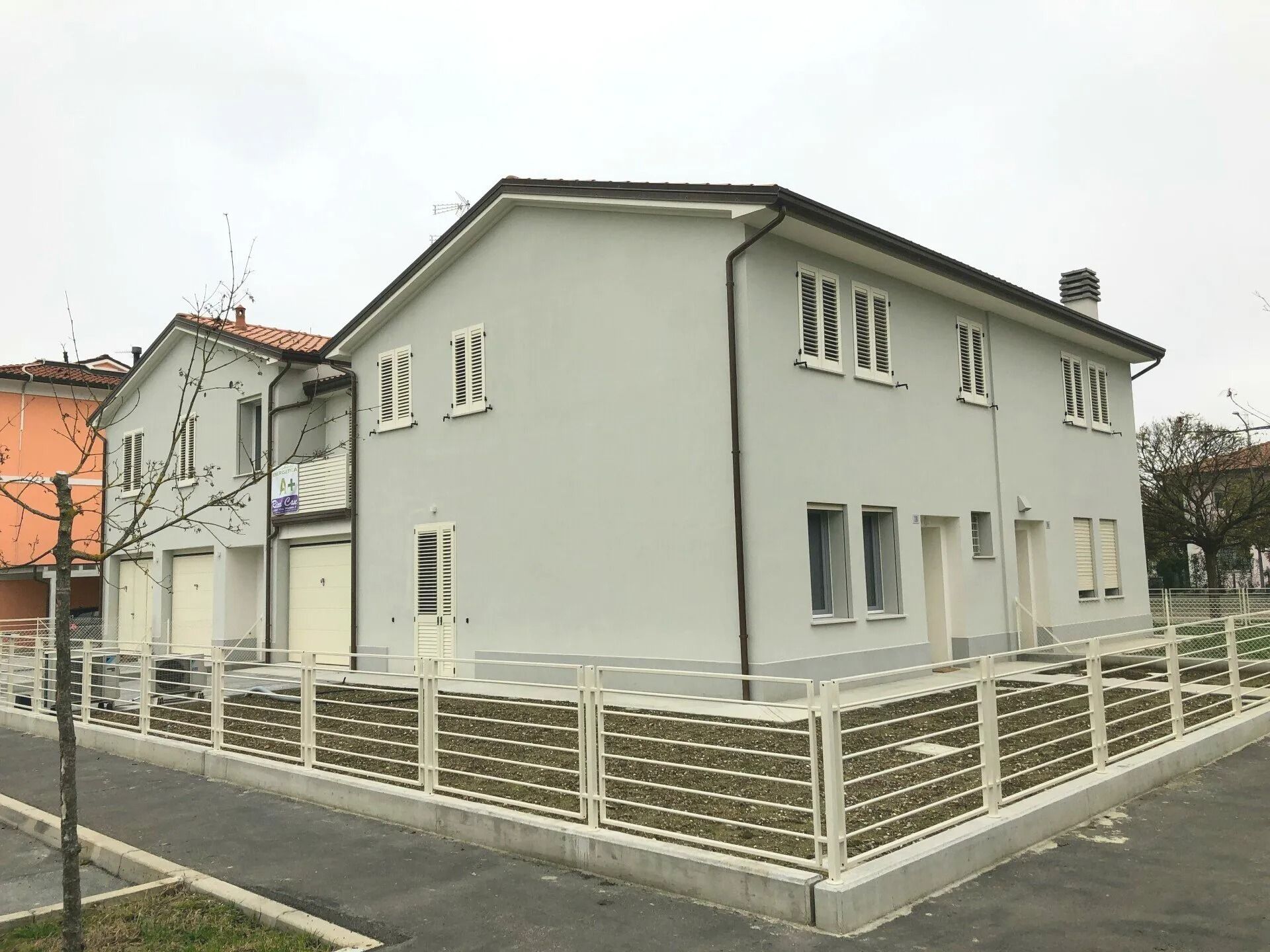 Casa bianca a due piani con giardino recintato, situata in una strada tranquilla.