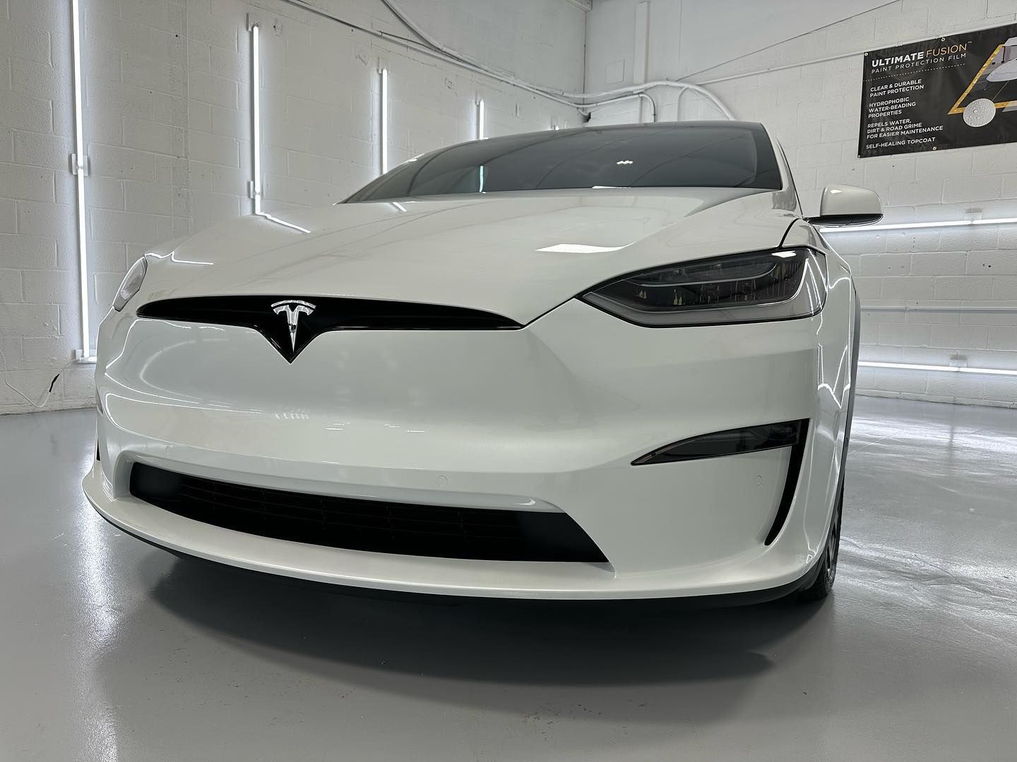a white tesla model s is parked in a garage .