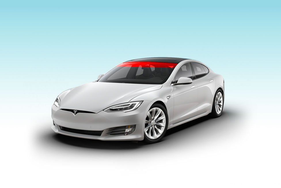 a white tesla model s with a red light on the windshield .