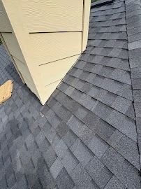 Roof shingles around a beige dormer on a house