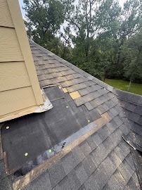 Damaged roof shingles around a chimney, with exposed underlayment on a sloped roof