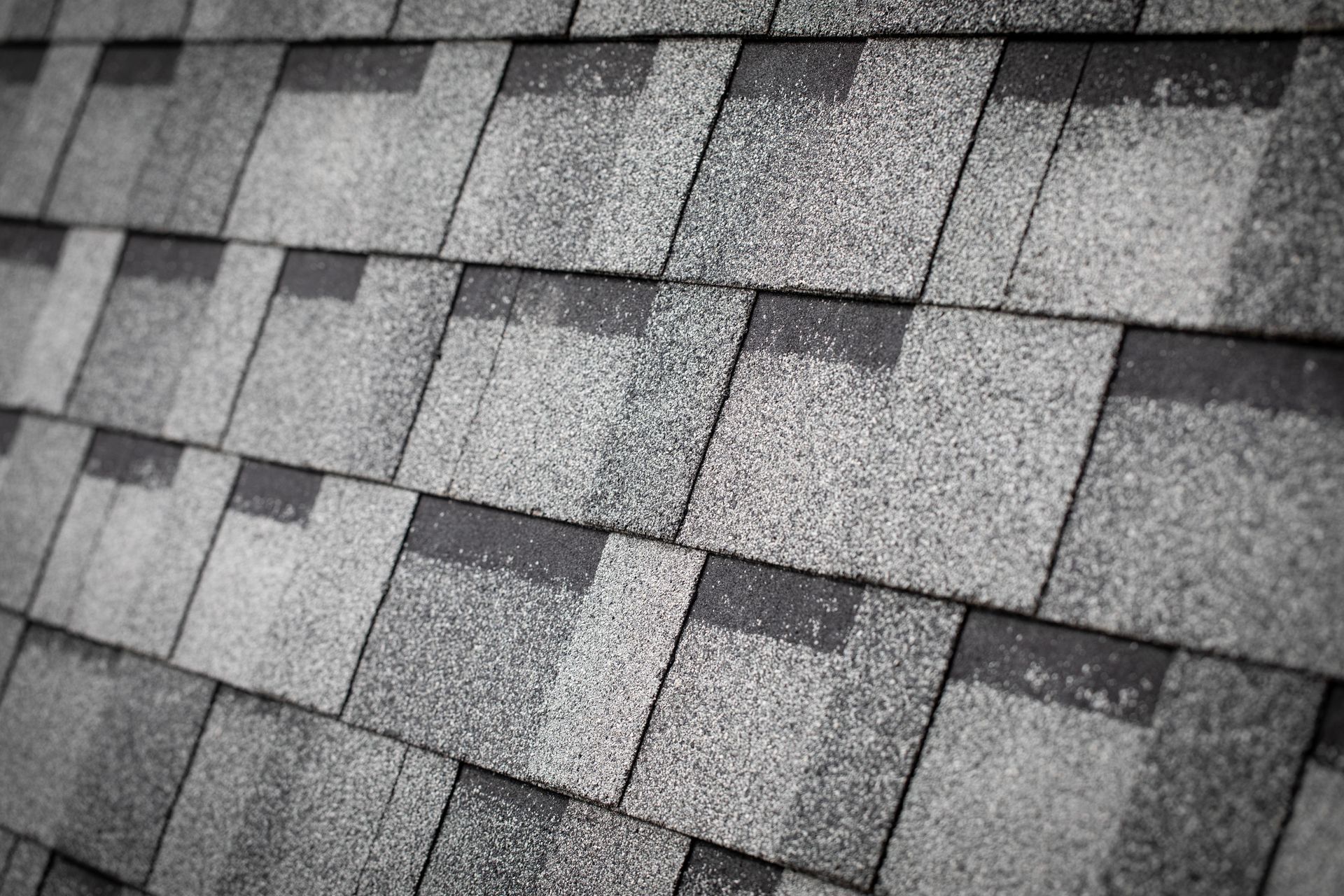 Close-up of gray asphalt roof shingles with overlapping rectangular tiles