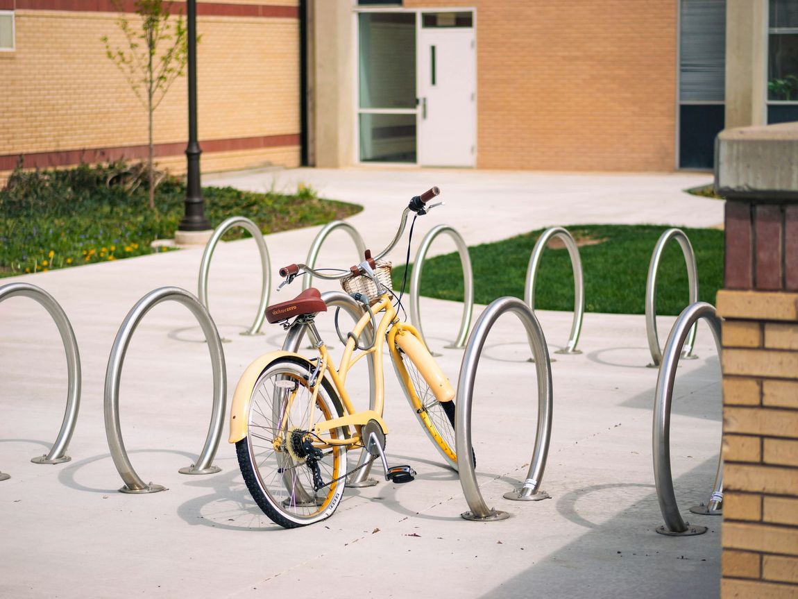 Yellow bicycle locked to a curved metal rack outside a brick building